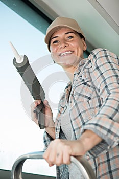 beautiful female construction worker using caulking gun
