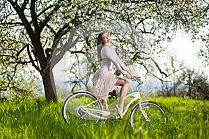 Beautiful female cyclist with retro bicycle in the spring garden