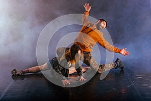 The beautiful female dancer is laying on the floor while her male partner performs an exotics unique modern art moves over her