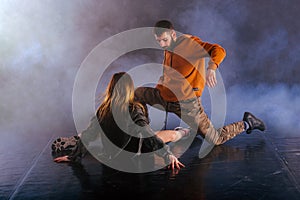 The beautiful female dancer is laying on the floor while her male partner performs an exotics unique modern art moves over her