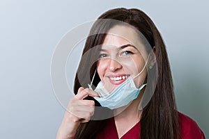 Beautiful female dentist removing mask and smiling