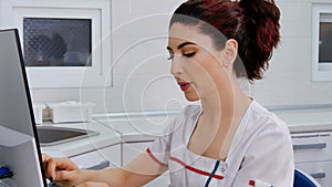 Beautiful female dentist use computer to make prescriptions and examine patient