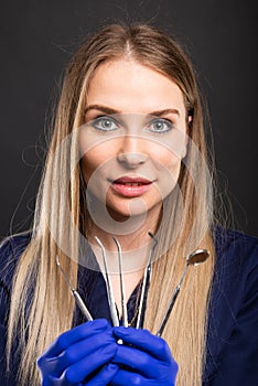 Beautiful female dentist wearing scrubs showing tools