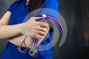 beautiful female doctor or medical student in blue uiform with stethoscope against dark background photo