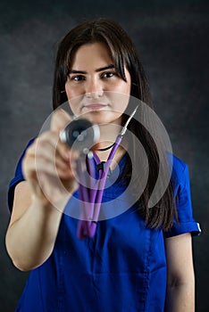 beautiful female doctor or medical student in blue uiform with stethoscope against dark background photo