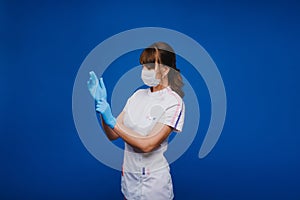 Beautiful female doctor or nurse wearing protective mask and latex or rubber gloves on grey background with copyspace