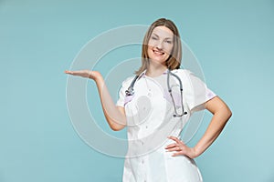 A beautiful female doctor with a stethoscope points to the place where there will be important information, on a blue