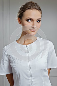 Beautiful female doctor in white clothes. Portrait of attractive medic in white robe