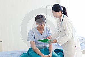 Beautiful female doctor in white medical coat is consulting her patient, showing the result of health