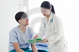 Beautiful female doctor in white medical coat is consulting her patient, showing the result of health