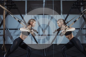 Sporty woman doing TRX exercises in the gym