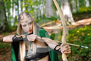 Beautiful female elf archer in the forest hunting with a bow