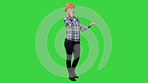 Beautiful female engineer in hardhat havin a phone call correcting the project on a Green Screen, Chroma Key.