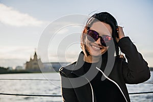 Beautiful female enjoying her free time by the river. Girl Outdoor Lifestyle. Young woman with black hair wearing