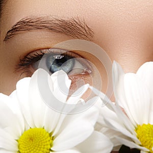 Beautiful female eye. Clean skin, fashion natural make-up. Good vision. Spring natural look with chamomile flowers