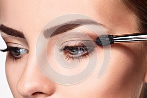 Beautiful female eyes with bright blue make-up and brush