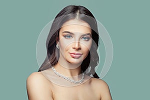 Beautiful female face. Fashion model woman with silver jewelry earrings and necklace on blue background