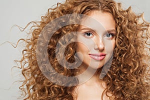 Beautiful female face. Fashion portrait of young model with curly long brown hairstyle on white background. Woman with wavy hair