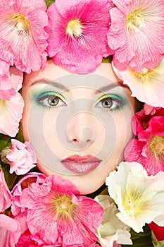 Beautiful female face with pink, red and white mallow flowers fr
