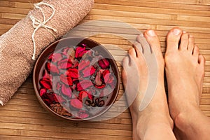 Beautiful female feet, spa salon, pedicure procedure with petals of red rose flower