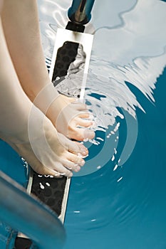 Beautiful female feet on the steps of the pool