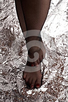 Beautiful female feets in mesh tights. Stock photo fashionable black mesh tights and sexy foots of a young girl