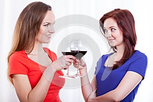 Beautiful female friends raising glasses of red wine