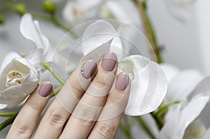 Beautiful female hand with beige nail design.