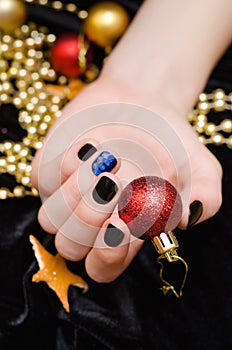 Beautiful female hand with black and blue nail design. Christmas manicure.