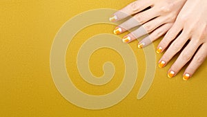 Beautiful Female Hands with bright orange Manicure like Candy Corn. Manicured Nails with Yellow Gel Polish. Halloween