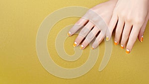 Beautiful Female Hands with bright orange Manicure like Candy Corn. Manicured Nails with Yellow Gel Polish. Halloween