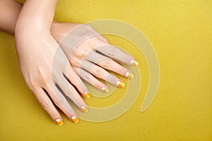 Beautiful Female Hands with bright orange Manicure like Candy Corn. Manicured Nails with Yellow Gel Polish. Halloween