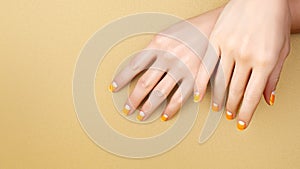 Beautiful Female Hands with bright orange Manicure like Candy Corn. Manicured Nails with Yellow Gel Polish. Halloween