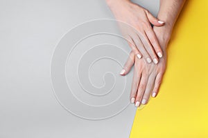 Beautiful female hands with a classic matte manicure on a gray-yellow background