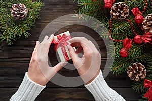 Beautiful female hands holding a Christmas present in box with red bow.