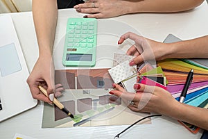 beautiful female hands with manicure working with color swatches to design rooms on the table