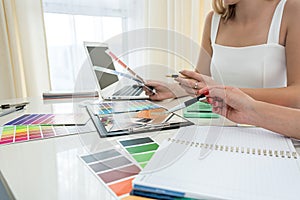 beautiful female hands with manicure working with color swatches to design rooms on the table