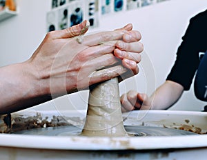 Beautiful female hands over the potter`s wheel. Sculpt from clay in a pottery workshop. Traditional pottery craft. Ceramics