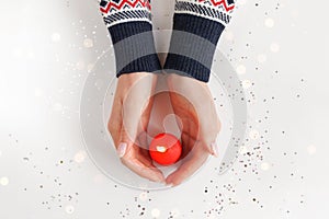 Beautiful female hands with red burning candle. Warmth and love concept. Christmas or Valentine& x27;s day background