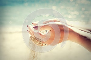 Beautiful female hands and the sand on the sea background