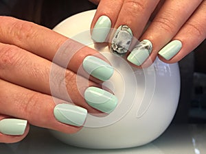 beautiful female hands with turquoise manicure and fashionable design.