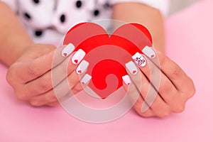 Beautiful female hands with white manicure, hearts design