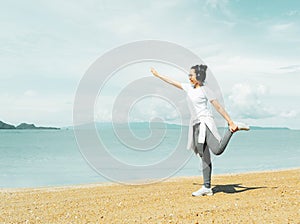 Beautiful female jogger doing yoga during the morning training on the beach,workout before the morning jog along the seafront