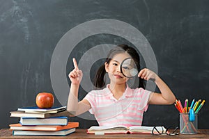 Beautiful female kid student showing magnifier