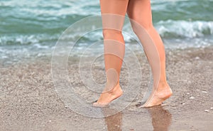 Beautiful female legs on the background of the sea. Saxy girl`s legs near the sea on the sand.