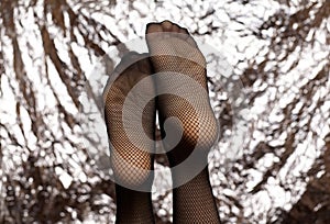 Beautiful female legs in mesh tights. Stock-fashionable black mesh tights and sexy feets of a young girl