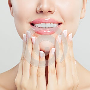 Beautiful female lips with glossy pink makeup and manicured hands with french manicure nails, closeup portrait