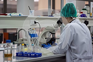 Beautiful female medical or scientific researcher or woman doctor looking through a microscope in a laboratory. Young scientist d