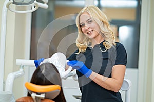 Beautiful female model advertising teeth whitening in a dental clinic with professional equipment