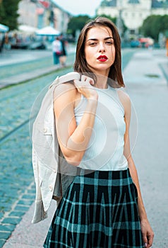 Beautiful female model hold the white suit across sholder in summer city in Europe. Trendy woman posing on the street photo